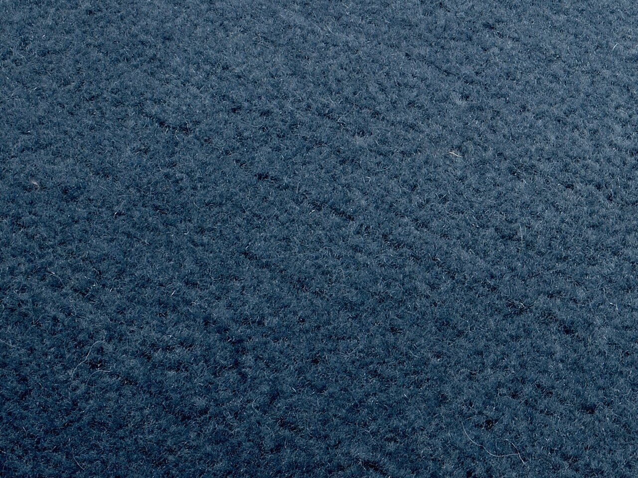 Nahaufnahme eines blauen, texturierten Stoffes, perspektivisch von oben betrachtet.