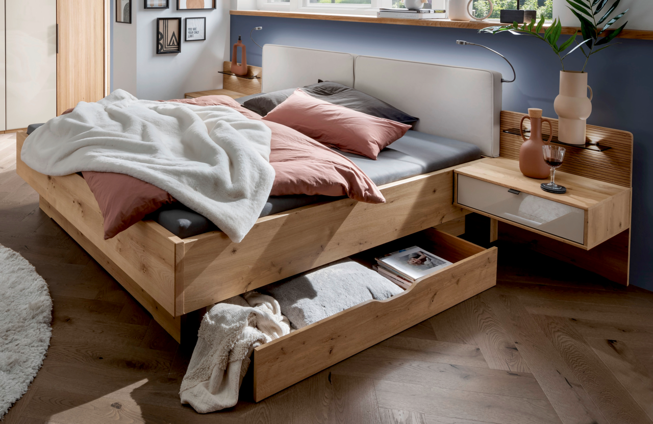 Venda Großraum-Bettschubkasten NEW YORK Großraum-Bettschubkasten aus Holz in einem modernen Schlafzimmer, mit Bettwäsche und Kissen, aus der Perspektive von vorne rechts.