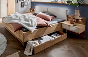 Großraum-Bettschubkasten aus Holz in einem modernen Schlafzimmer, mit Bettwäsche und Kissen, aus der Perspektive von vorne rechts.