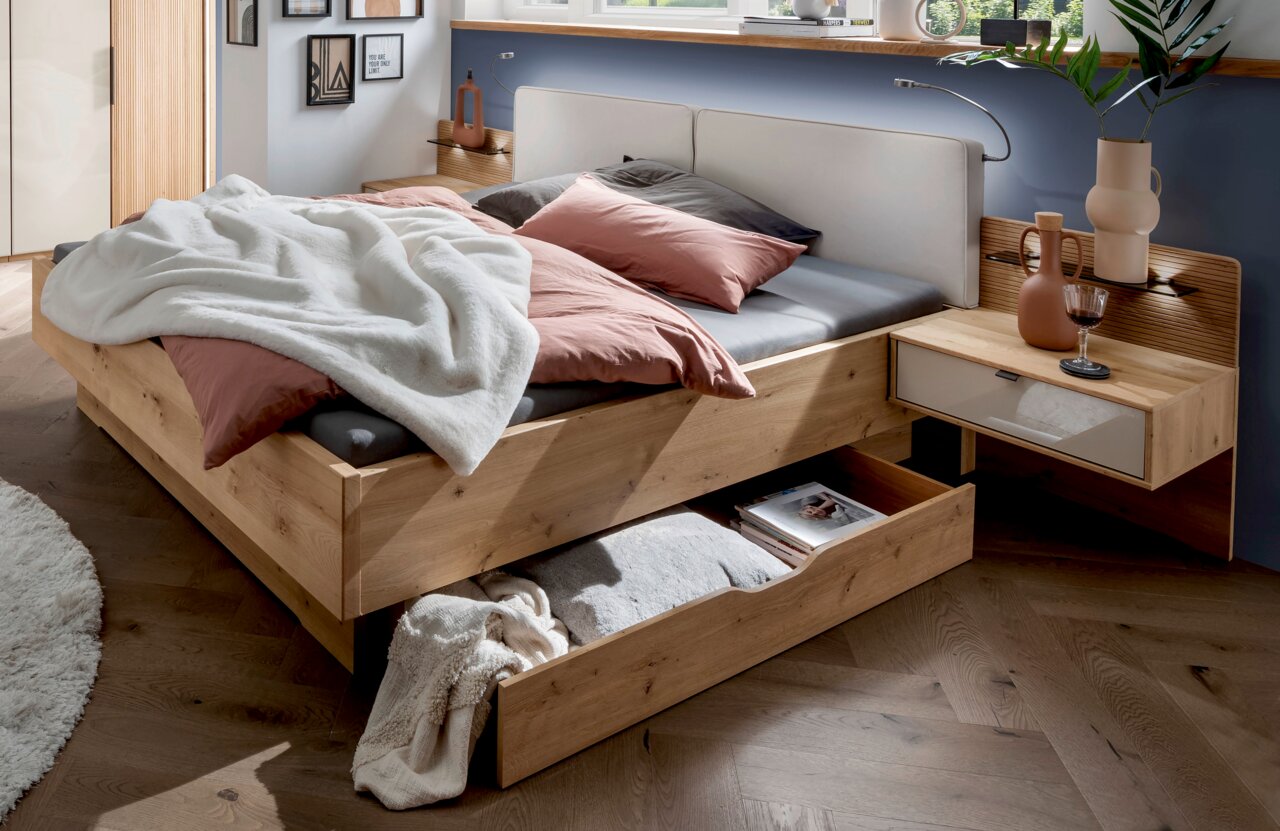 Venda Großraum-Bettschubkasten NEW YORK Großraum-Bettschubkasten aus Holz in einem modernen Schlafzimmer, mit Bettwäsche und Kissen, aus der Perspektive von vorne rechts.