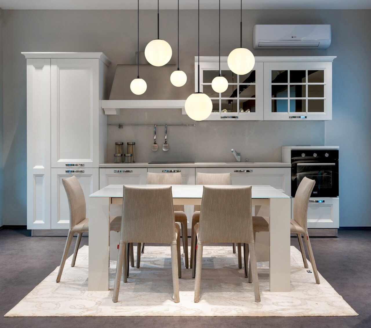 Moderne Hängeleuchte mit mehreren kugelförmigen Lampen, die über einem Esstisch in einer stilvollen Küche hängt. Perspektive von vorne.