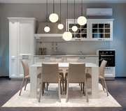 Moderne Hängeleuchte mit mehreren kugelförmigen Lampen, die über einem Esstisch in einer stilvollen Küche hängt. Perspektive von vorne.