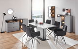 Moderne Esszimmermöbel in einem hellen Raum mit Meerblick, bestehend aus einem weißen Tisch, schwarzen Stühlen und grauen Sideboards. Perspektive: Frontalansicht.