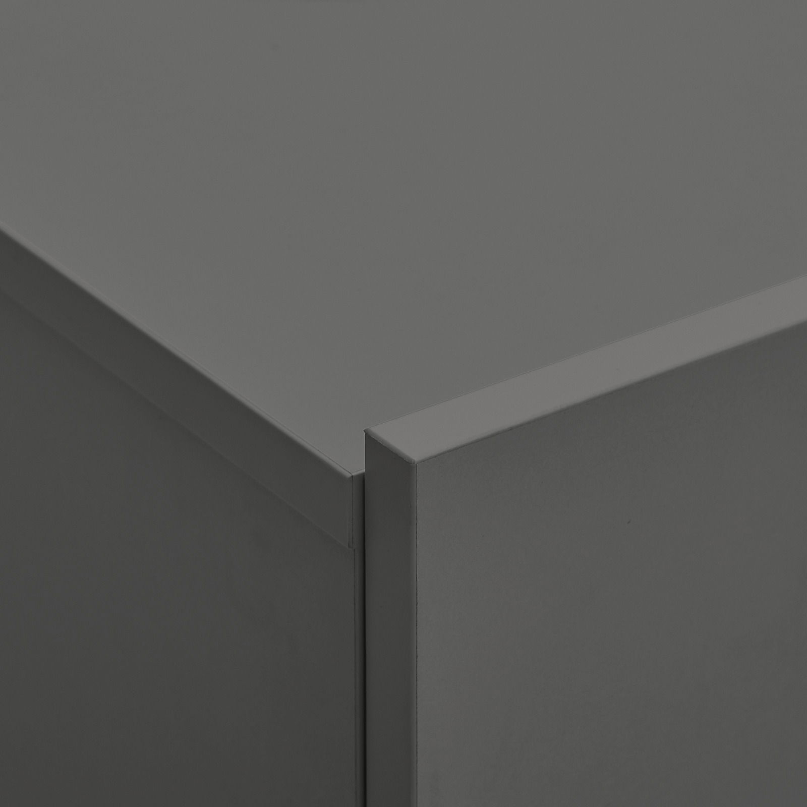 Nahaufnahme einer Ecke eines grauen Hängeschuhschranks aus Metall, perspektivisch von oben fotografiert.