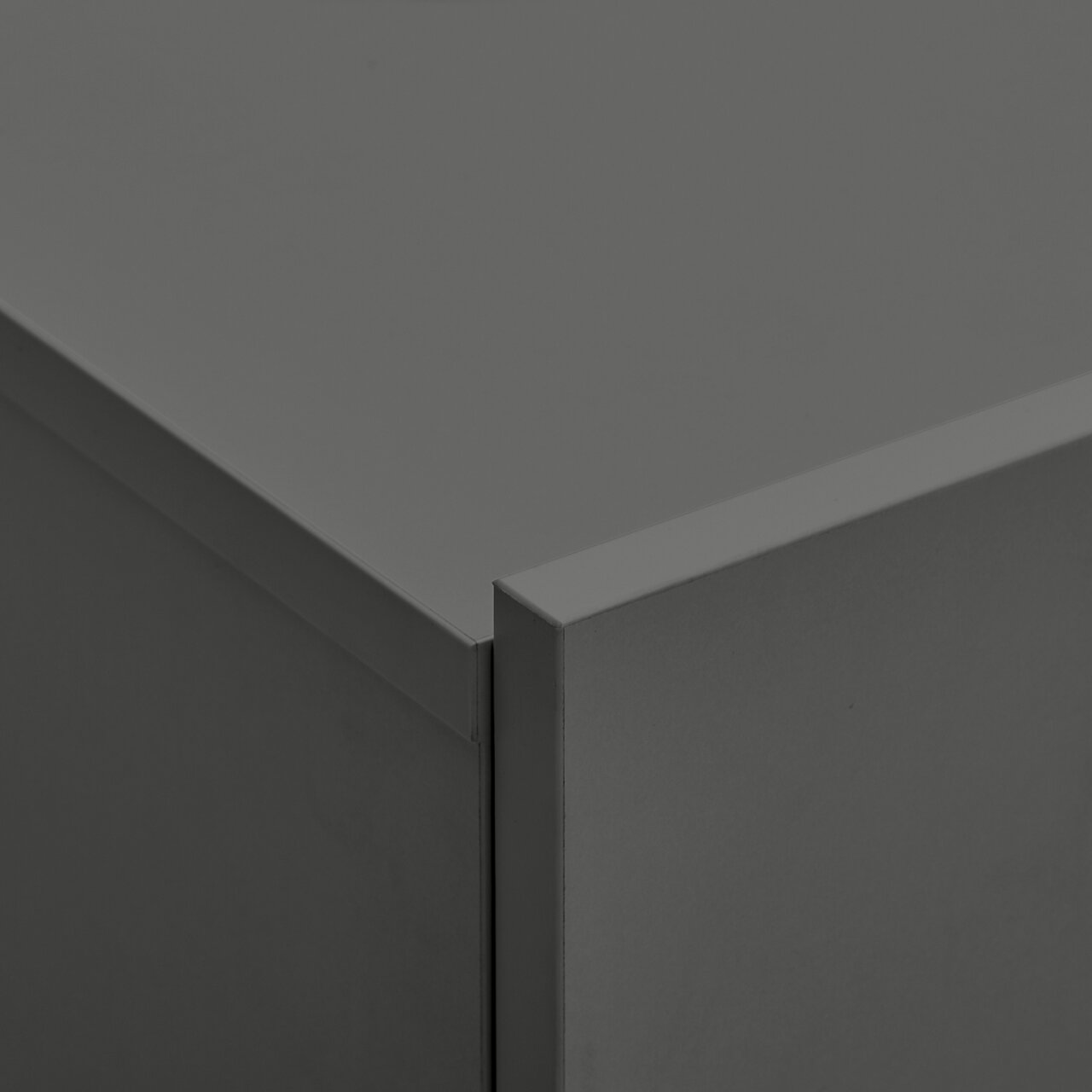 Close-up van een hoek van een grijze metalen hangende schoenenkast, vanuit een perspectief van bovenaf gefotografeerd.