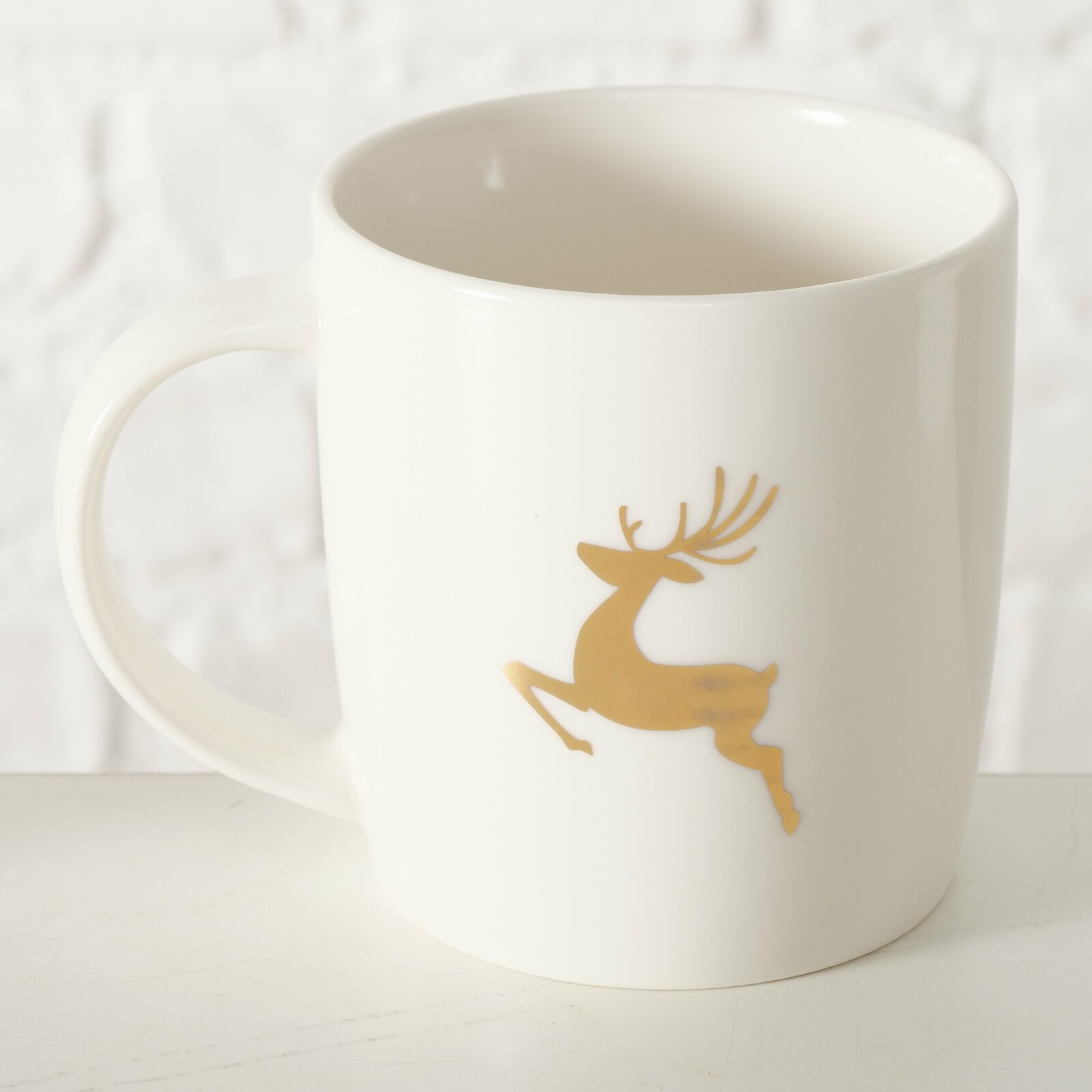 Weißer Becher mit goldfarbenem Rentiermotiv, seitliche Perspektive