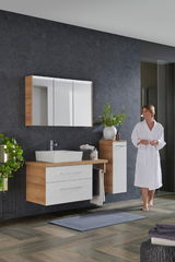 Moderne Badkombination mit Holz- und Weißtönen, bestehend aus einem Waschtisch mit Spiegel und Schrank, seitliche Perspektive.