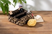 Kosmetiktasche mit Leopardenmuster, gefüllt mit Make-up-Pinseln und Fläschchen, auf einem Holztisch von oben fotografiert.