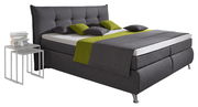 Boxspringbett in dunklem Grau mit grünem Akzent, seitliche Perspektive