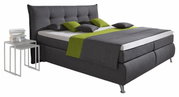 Boxspringbett in dunklem Grau mit grünem Akzent, seitliche Perspektive