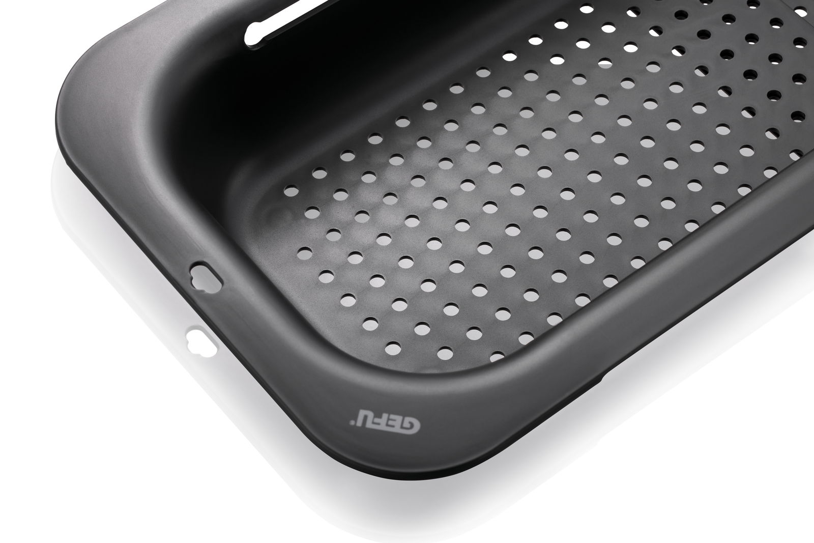 Nahaufnahme eines schwarzen Spülbeckensiebs mit runden Löchern, perspektivisch von oben fotografiert.