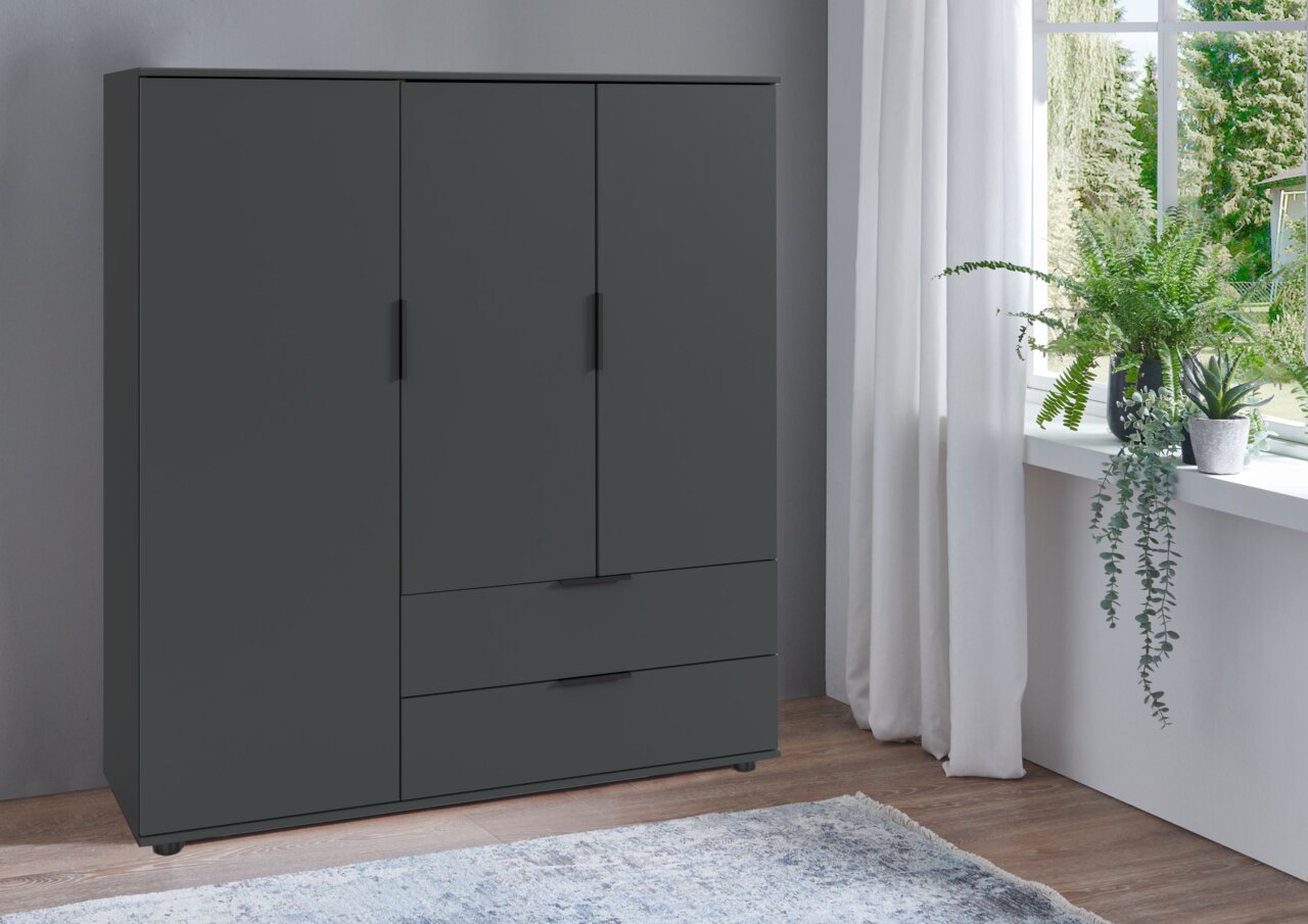 Z2 Highboard EASY PLUS Modernes, dunkelgraues Highboard mit drei Türen und zwei Schubladen, seitliche Perspektive, neben einem Fenster mit Pflanzen.