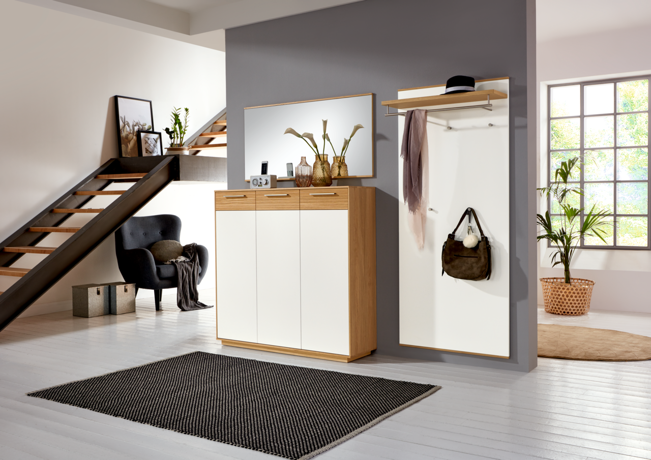 VOSS XL-Schuhkommode LOVENO Moderne Garderobeneinrichtung mit Schuhschrank, Spiegel und Garderobenpaneel in einem stilvollen Raum mit Treppe, aus der Perspektive des Eingangsbereichs betrachtet.