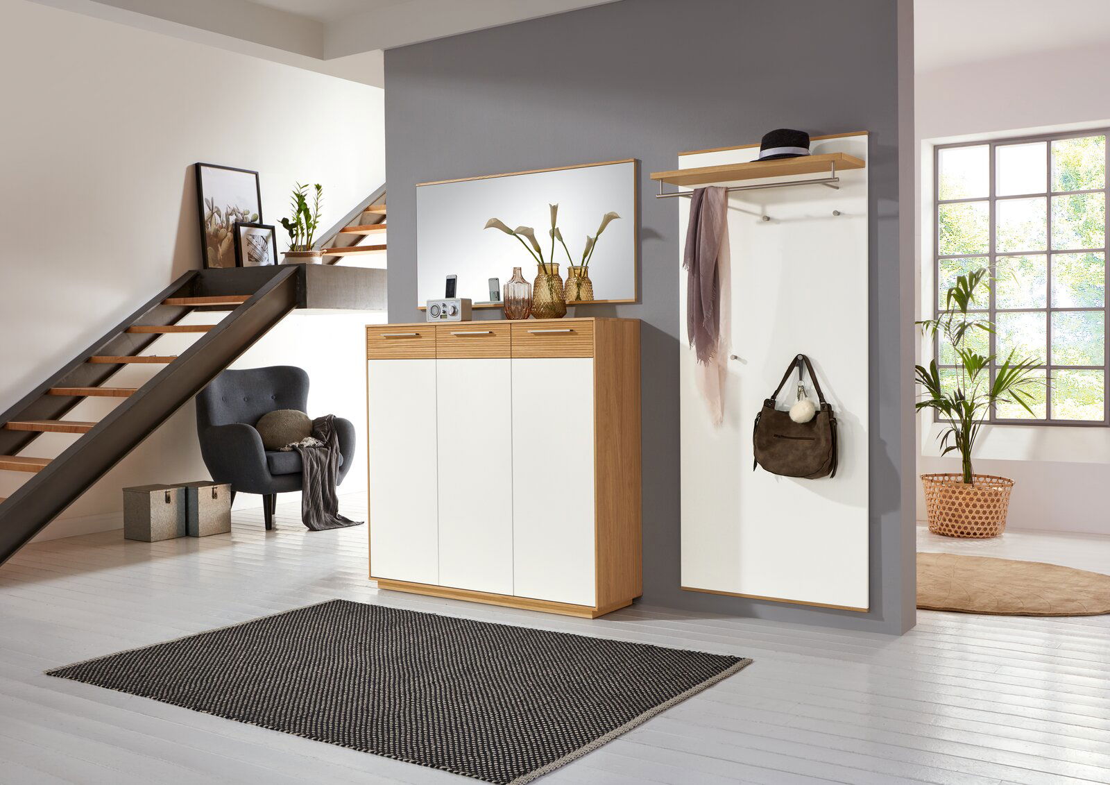 VOSS Dielenschrank LOVENO Moderne Garderobeneinrichtung mit Schuhschrank, Spiegel und Garderobenpaneel in einem stilvollen Raum mit Treppe, aus der Perspektive des Eingangsbereichs betrachtet.