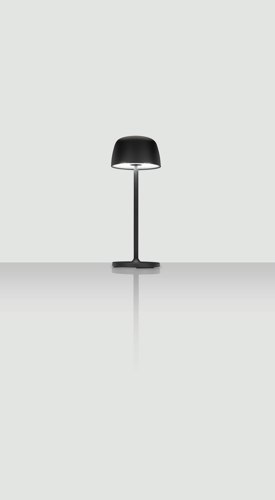 Schwarze Akku-Tischleuchte mit modernem Design, frontal abgebildet auf einer reflektierenden Oberfläche.
