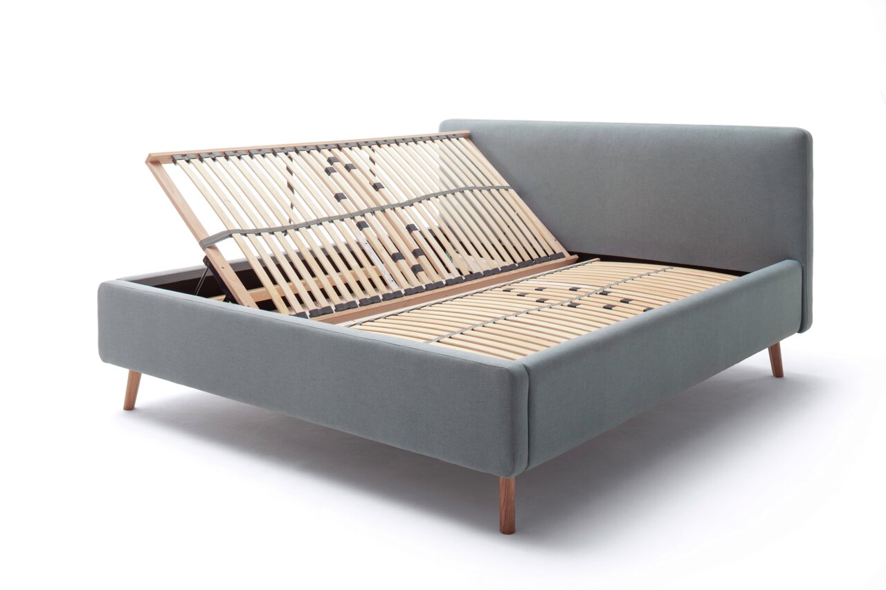 Polsterbett in grauem Stoff mit hochgeklapptem Lattenrost, seitliche Perspektive
