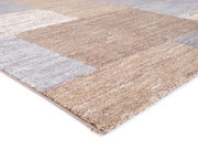 Nahaufnahme eines Frisé-Teppichs in Beige- und Grautönen, perspektivisch von der Seite aufgenommen.