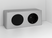 Silberne Steckdose mit zwei Anschlüssen, eine runde Abdeckung und eine Steckdose, in einer Ecke montiert.