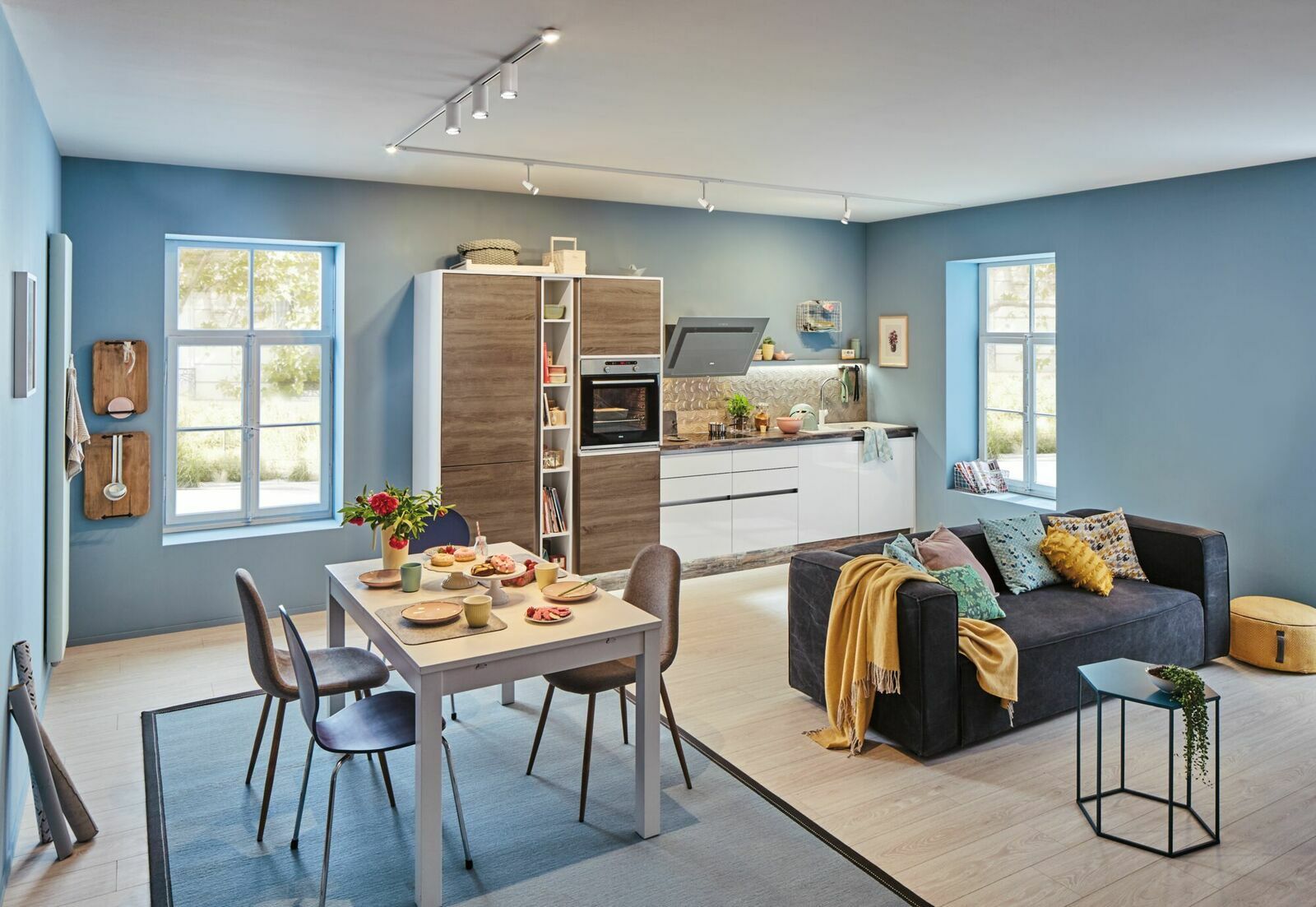 Moderne Wohnküche mit Schienensystembeleuchtung an der Decke, Perspektive von der Seite.