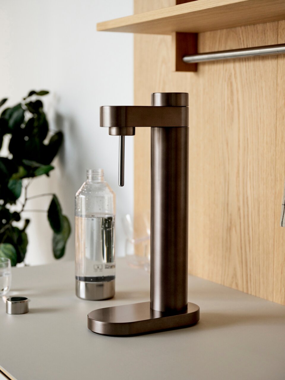 Dunkelbrauner Stelton Wassersprudler BRUS auf einer Küchenarbeitsplatte, seitliche Perspektive.