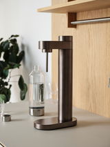 Dunkelbrauner Stelton Wassersprudler BRUS auf einer Küchenarbeitsplatte, seitliche Perspektive.