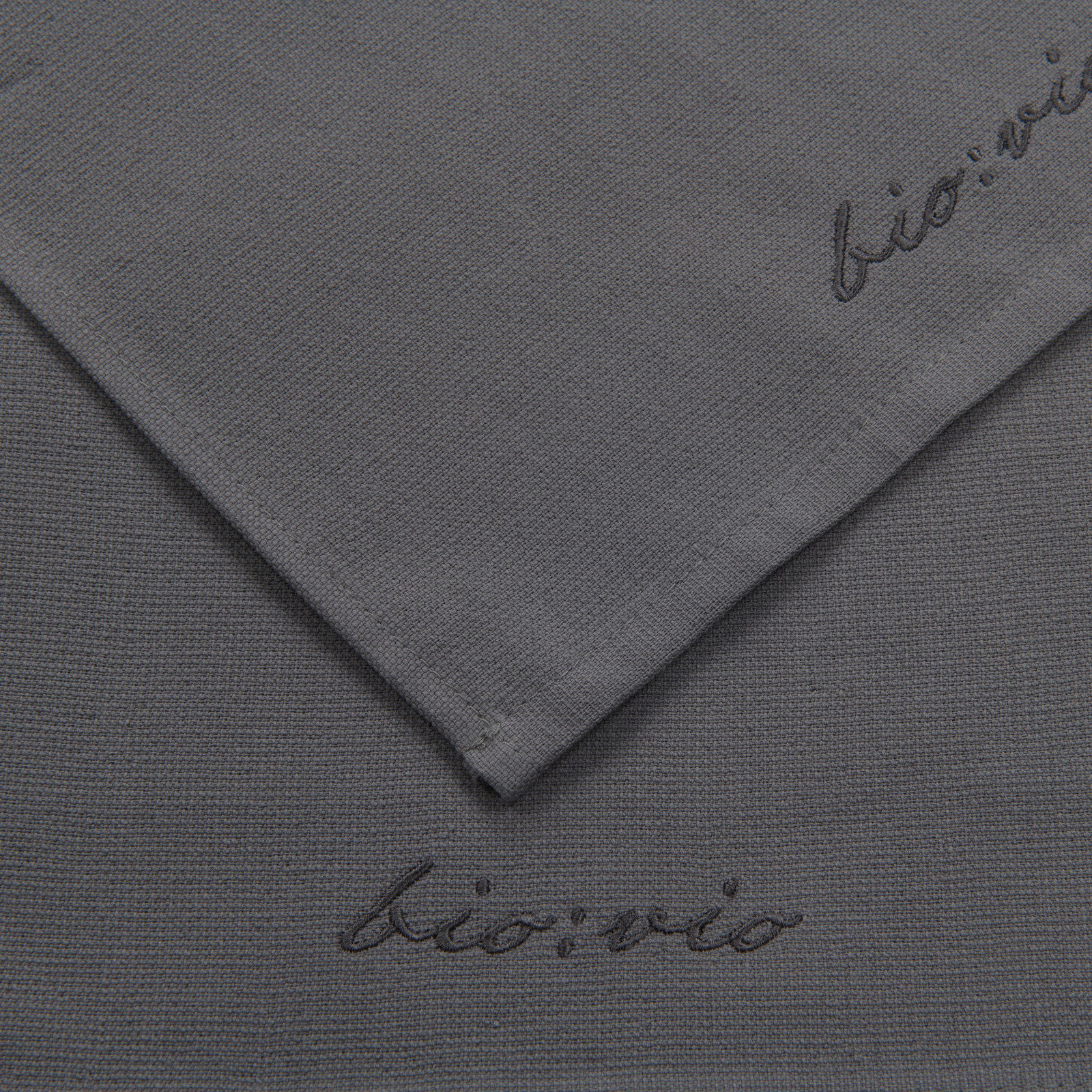 Graues Gästetuchset mit gesticktem Schriftzug 'bio:vio', aus der Vogelperspektive aufgenommen.