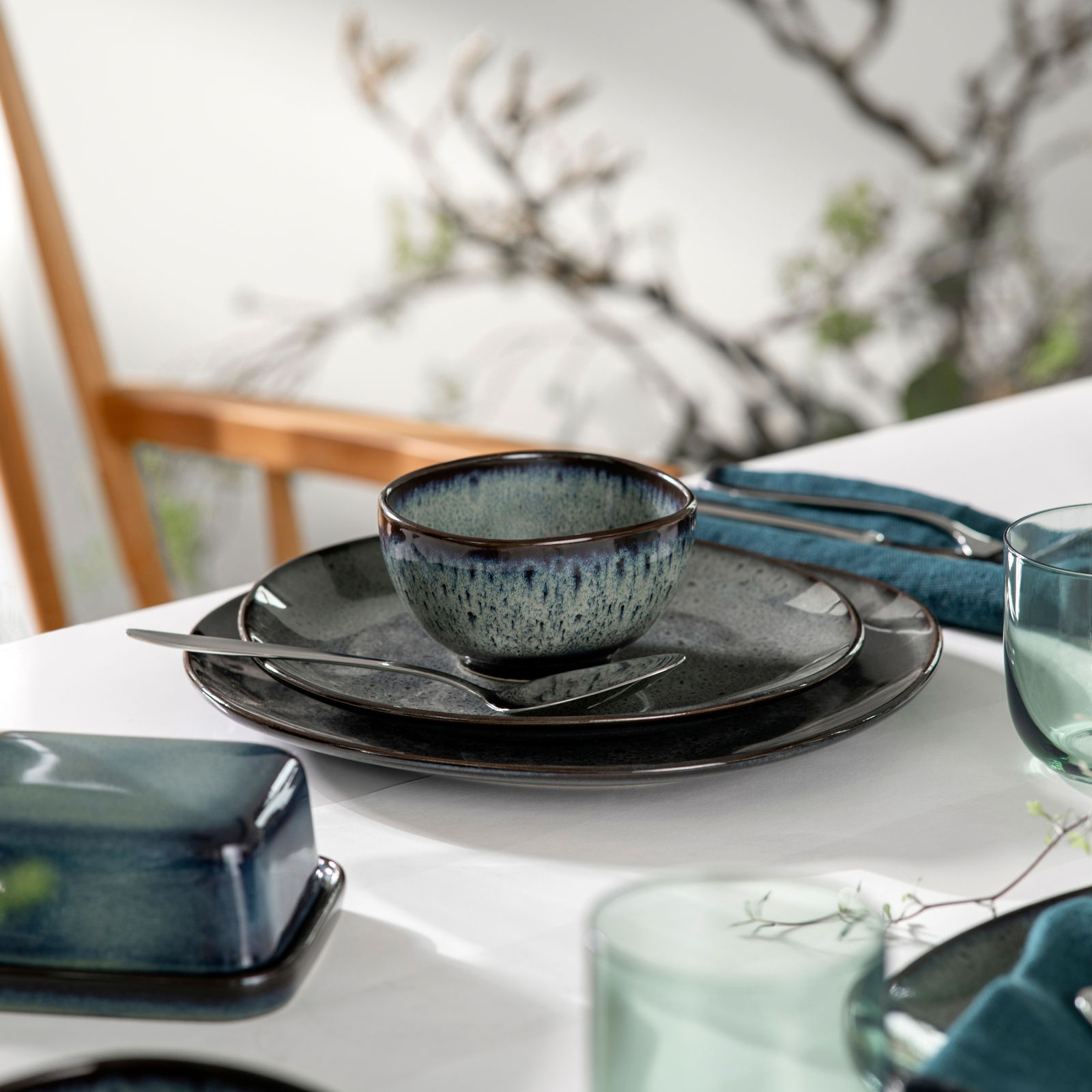 Dessertschale Lave 210ml grau, stilvoll auf einem gedeckten Tisch mit Besteck und Serviette, seitliche Perspektive