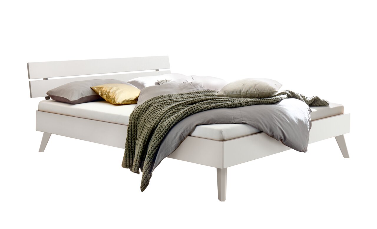 Modernes Bett mit weißem Holz- und Metallkopfteil, seitliche Perspektive, dekoriert mit Kissen und Decke.