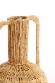 Nahaufnahme einer handgefertigten Vase aus geflochtenem Naturmaterial mit zwei Griffen, seitliche Perspektive