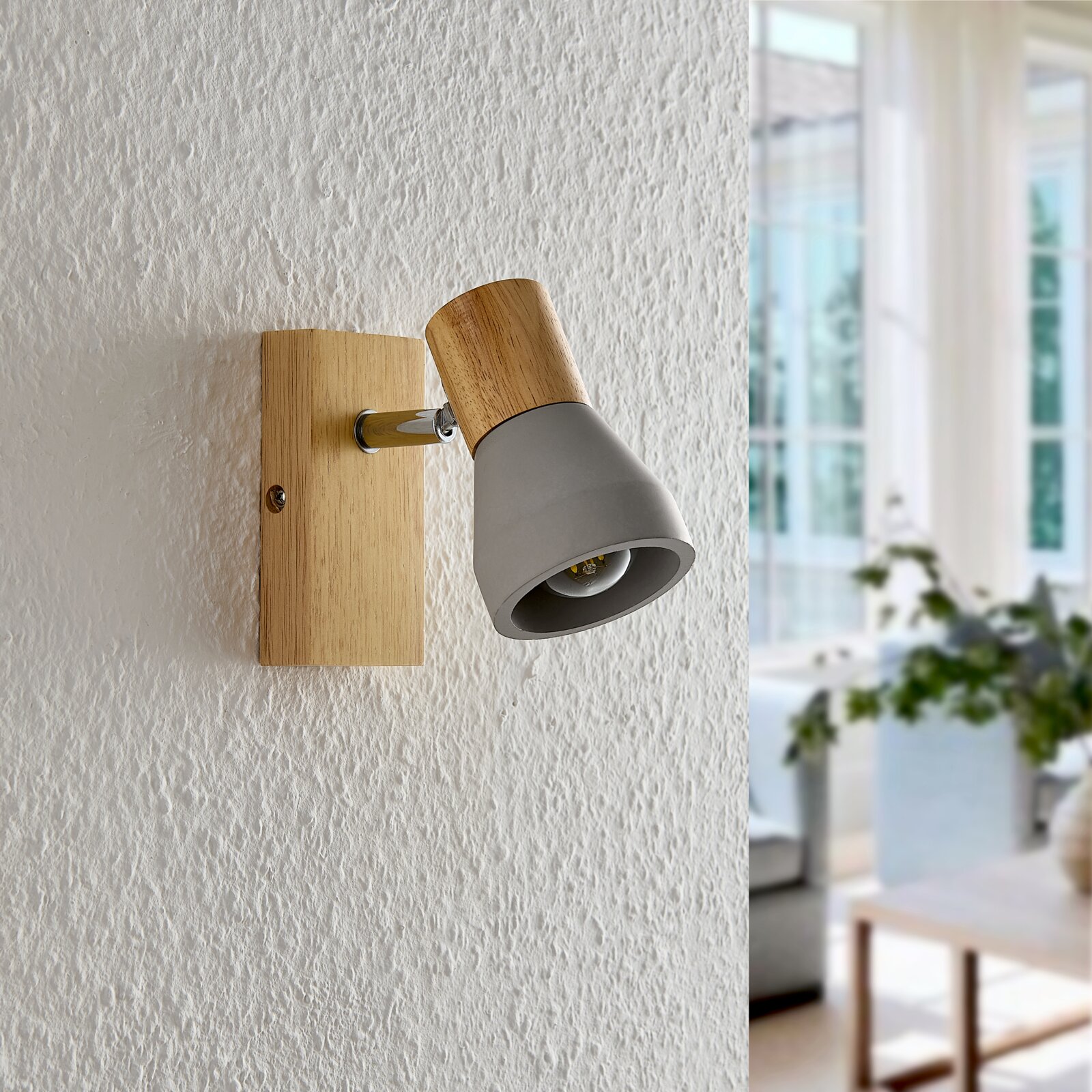 Moderner Wandstrahler aus Holz und Metall in seitlicher Perspektive, montiert an einer strukturierten weißen Wand, mit einem gemütlichen Wohnbereich im Hintergrund.