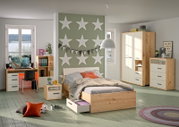 Moderner Kleiderschrank in einem stilvollen Schlafzimmer, aus hellem Holz mit weißen Türen, im Vordergrund ein Bett mit Stauraum, seitliche Perspektive.