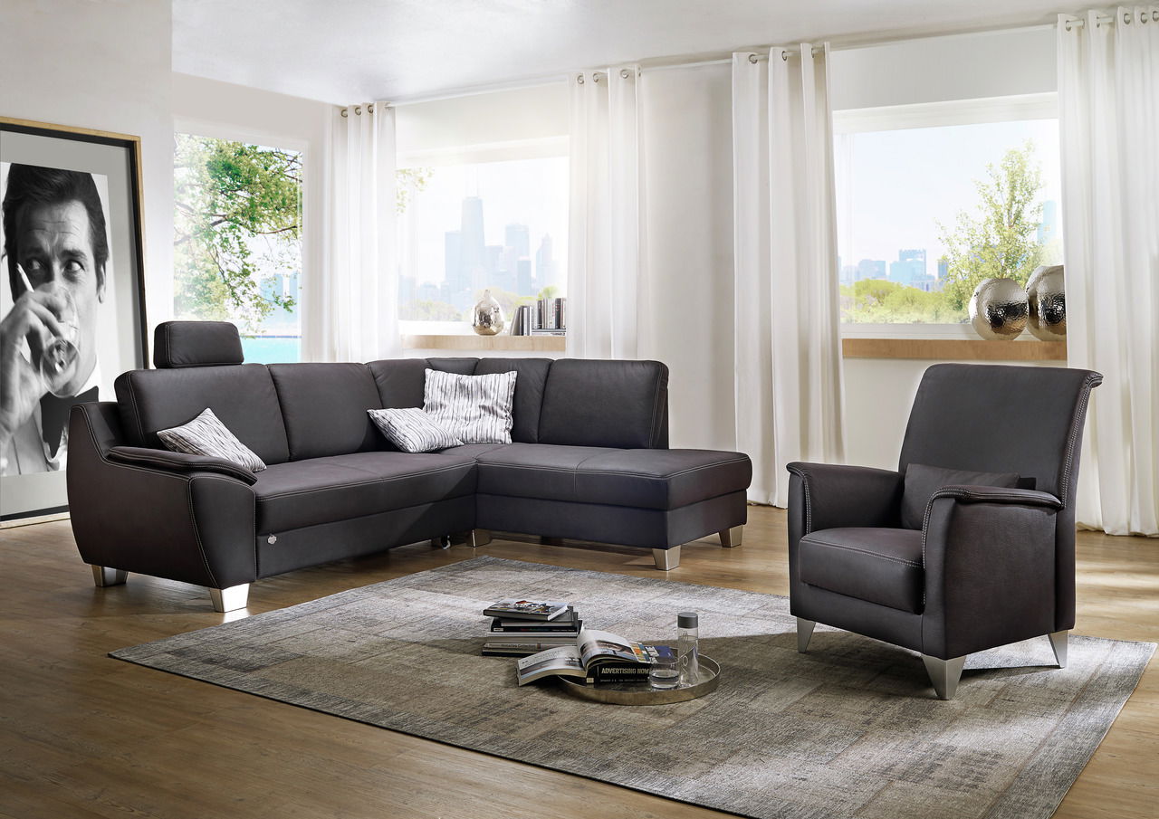 Landscape Ecksofa LIMONO Moderne Polsterrundecke in einem hellen Wohnzimmer mit großen Fenstern, ergänzt durch einen passenden Sessel. Perspektive von vorne.