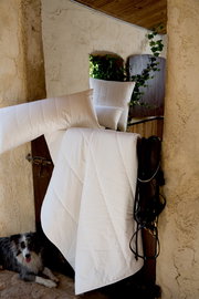 Sommerbettdecke und Kissen aus Bio-Baumwolle in einem rustikalen Innenhof, mit einem Hund im Vordergrund.