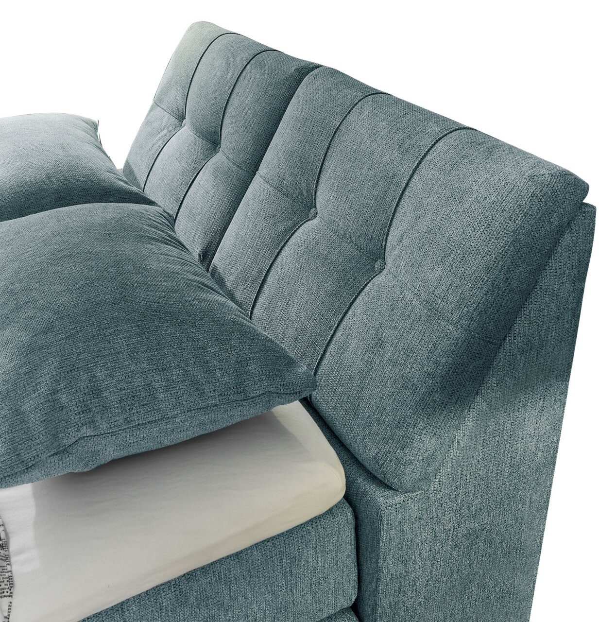 Nahaufnahme eines Boxspringbetts mit gepolstertem Kopfteil in blauer Stoffoptik, seitliche Perspektive