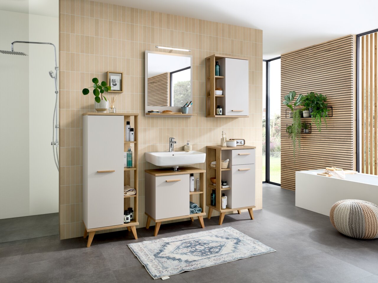 Moderne Badezimmeransicht mit TwinLED-Aufsatzleuchte über einem Spiegel, umgeben von stilvollen Schränken und Pflanzen, seitliche Perspektive.