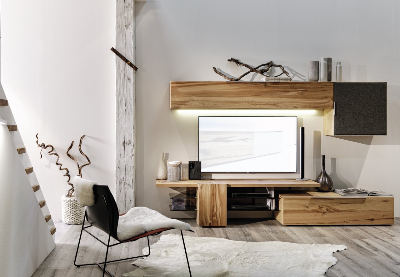 Moderne Wohnwand aus Holz ohne Beleuchtung, mit TV und Dekorationen, aus seitlicher Perspektive fotografiert.