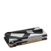 Gestapelte Wohndecke mit geometrischem Muster in Schwarz, Weiß und Braun, seitliche Perspektive