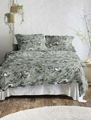 Bettwäsche-Set mit floralem Muster in Grün- und Weißtönen, auf einem Bett arrangiert, aus der Frontalperspektive fotografiert.