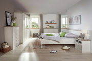 Helles Schlafzimmer mit einem 5-türigen Drehtürenschrank, Bett und Kommode in Holzoptik, seitliche Perspektive.