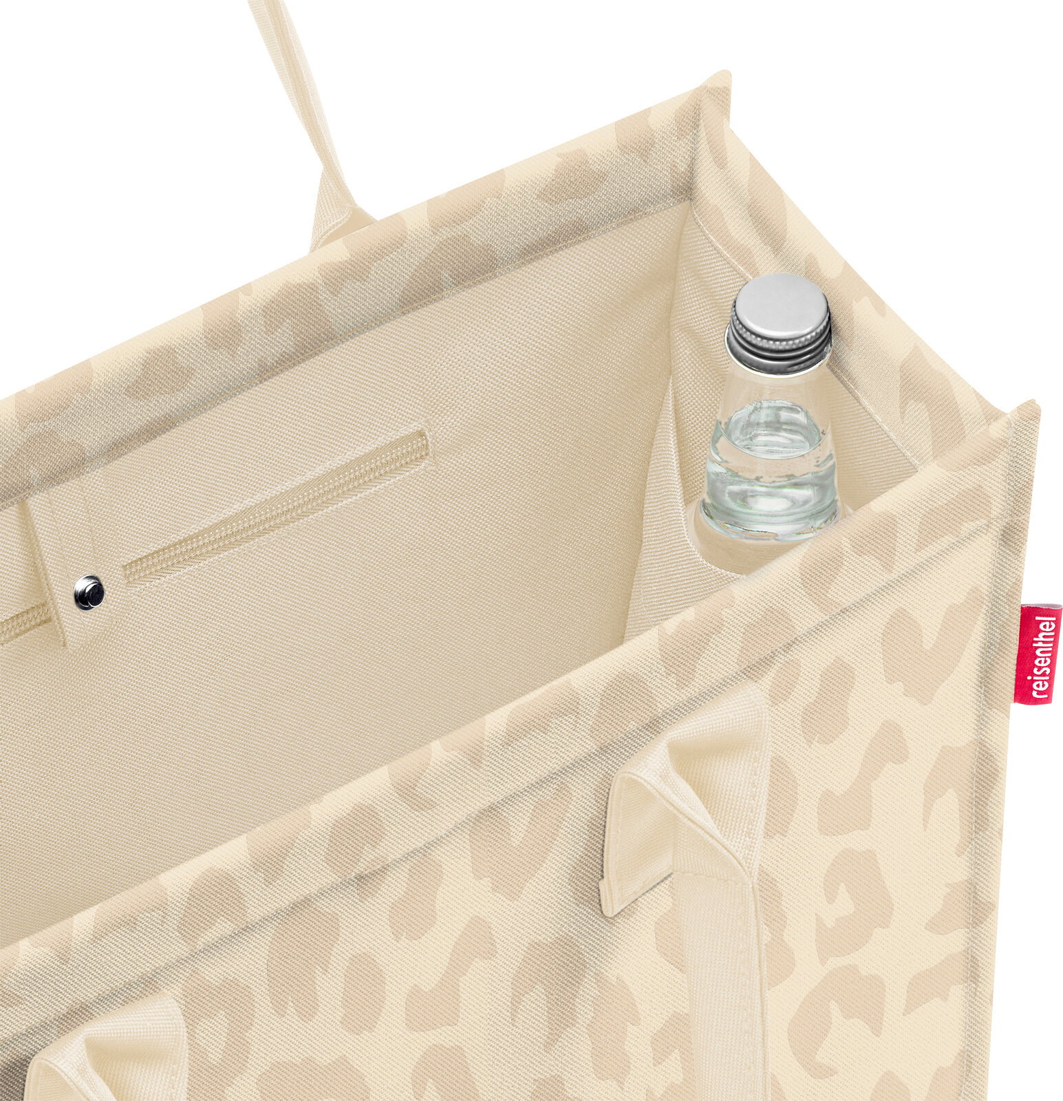 Blick von oben in eine beige gemusterte Einkaufstasche mit Innenfach und kleiner Flasche in der Ecke, Seitenansicht schräg von oben.