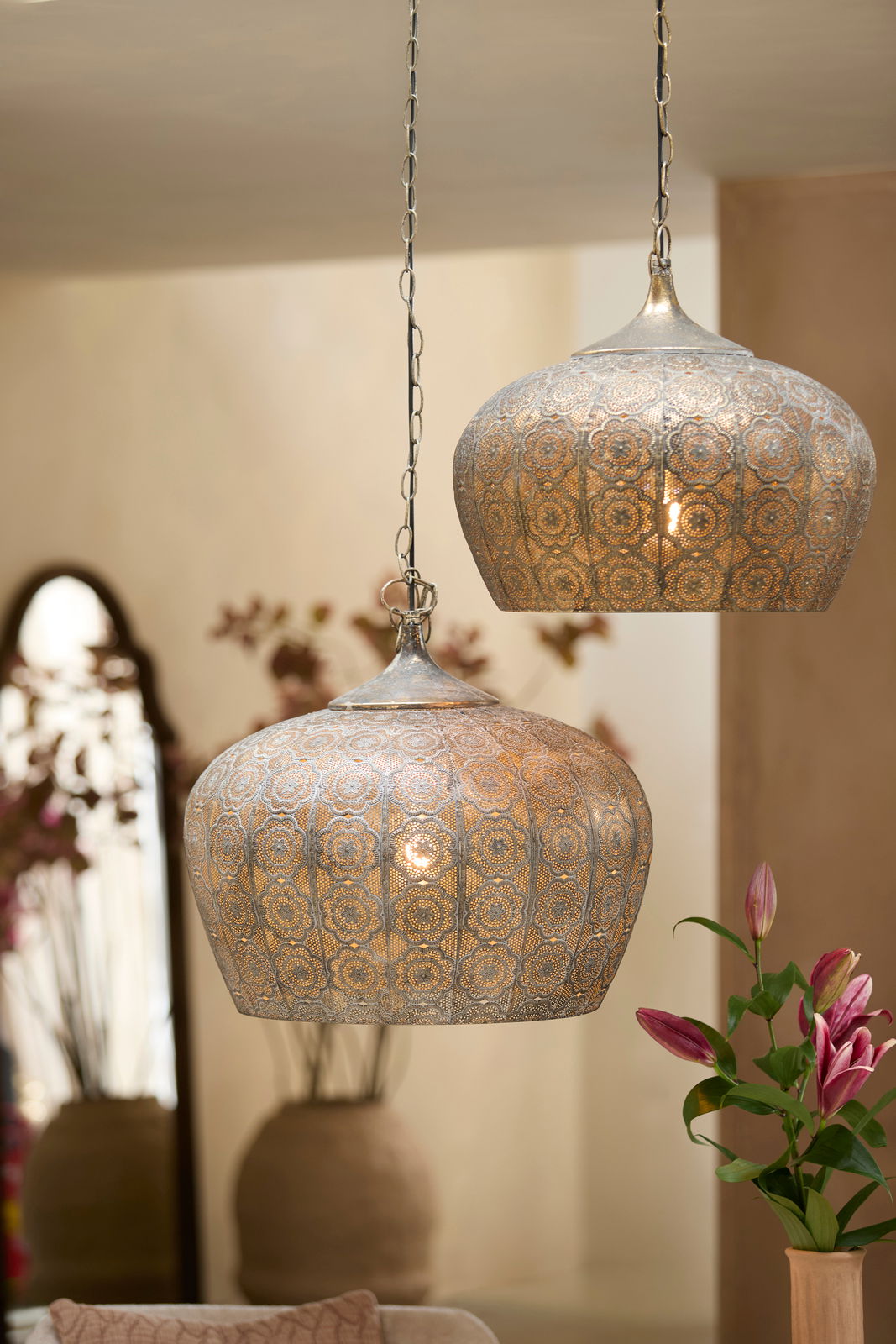 Zwei orientalische Hängeleuchten aus Metall mit filigranem Muster, von der Seite betrachtet, in einem stilvoll dekorierten Raum.