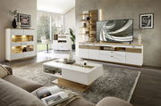 Moderne Wohnzimmer-Wandkombination in Weiß und Holzoptik, mit TV-Schrank, Regalen und dekorativer Beleuchtung, aus der Perspektive eines gemütlichen Wohnzimmers.