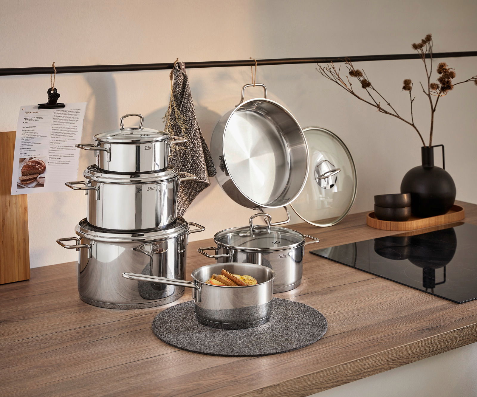 Topfset Alicante 5-tlg aus Edelstahl, bestehend aus mehreren Töpfen mit Deckeln, auf einer Küchenarbeitsplatte präsentiert. Perspektive von vorne.