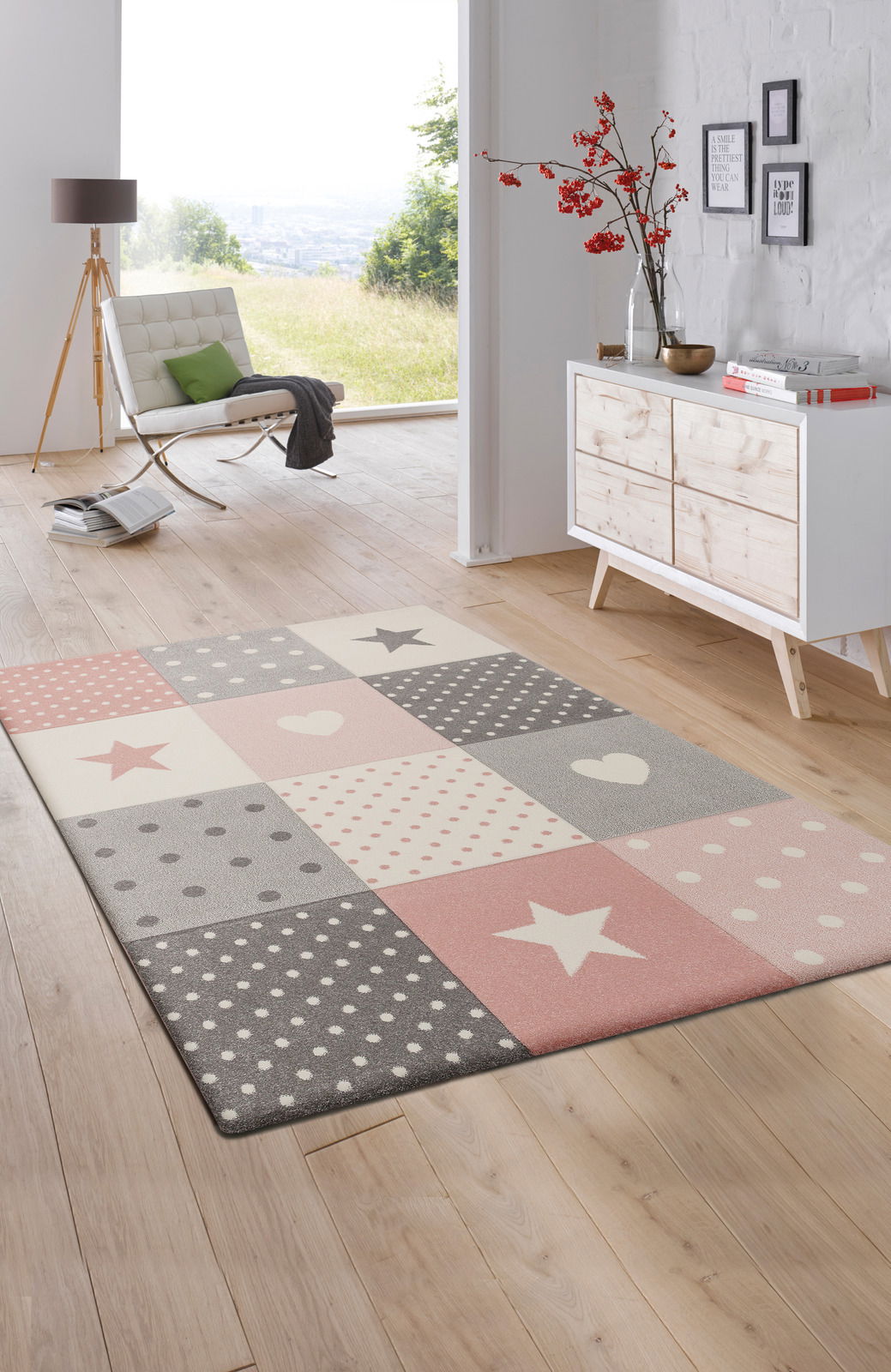 Kinderteppich mit rosa und grauen Sternen- und Punktmustern in einem modernen Wohnzimmer, Perspektive von oben.