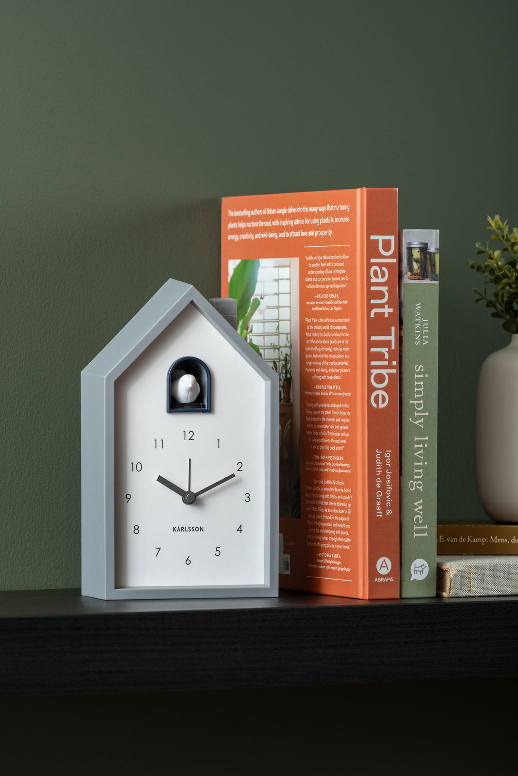 Moderner Wecker in Hausform mit schwarzem Zifferblatt und weißen Zeigern, seitliche Perspektive.