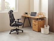 Moderner Schreibtisch mit Holzoberfläche und schwarzem Metallgestell, seitlich mit Schubladen, in einem hellen Raum mit ergonomischem Bürostuhl.