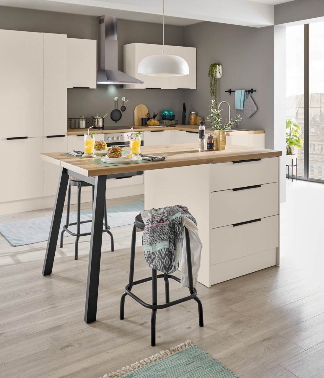 Moderne, lichte keuken met een kookeiland in wit en houtlook, zwarte handgrepen en barkrukken, gefotografeerd vanuit een licht verhoogd vooraanzicht/schuin perspectief.
