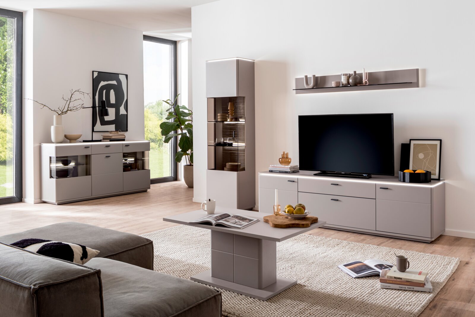 Modernes Wohnzimmer mit grauer Wohnwand (TV-Lowboard, Vitrine, Sideboard und Wandboard) und passendem Couchtisch, frontal aus leicht seitlicher Perspektive fotografiert