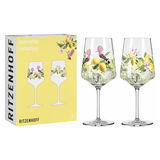 Zwei elegante Weingläser mit farbenfrohem Limoncello-Motiv, bestehend aus Zitronen und Blumen, neben der Verpackung mit gleichem Design, aus frontaler Perspektive.