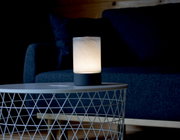 Akku-Windlicht auf einem Tisch vor einem Sofa, seitliche Perspektive
